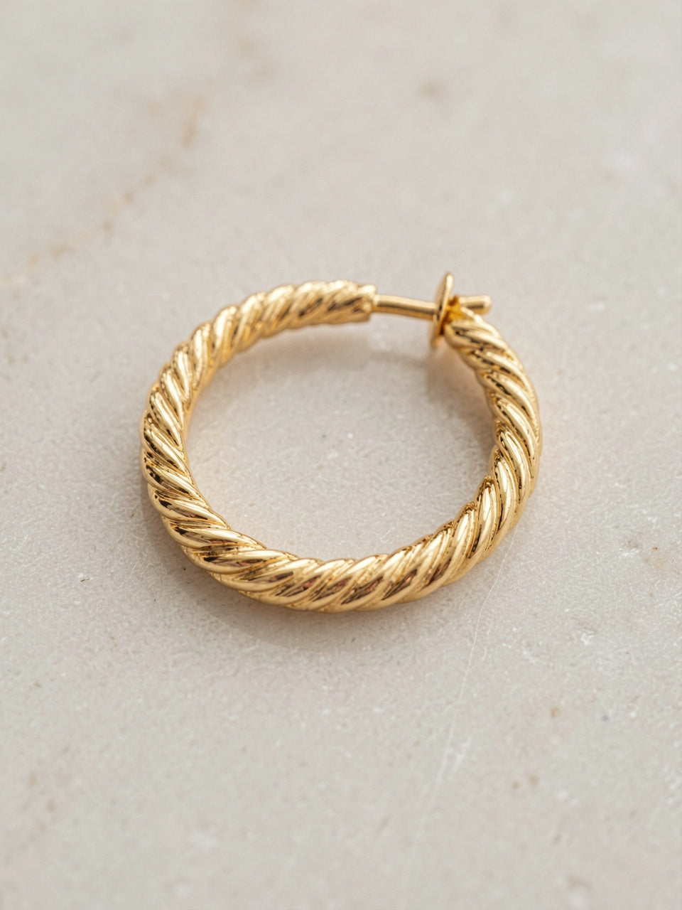 Close-up detail of textured braided gold hoop earring