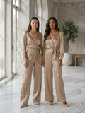 Two models wearing the satin twist-front top and wide-leg pants set in beige