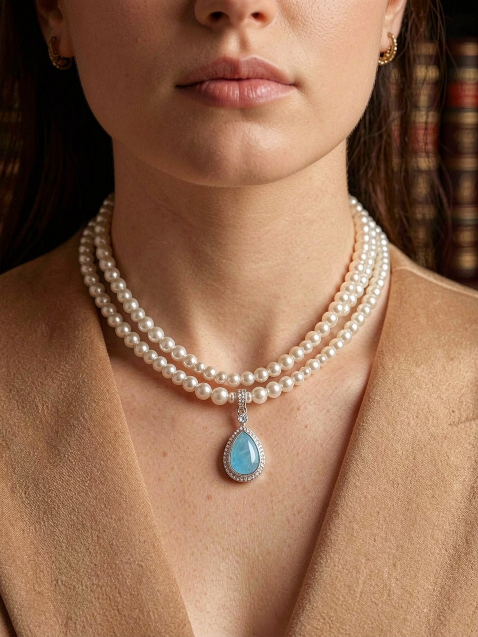 Primer plano de collar de perlas de dos hilos tipo choker color blanco/crema con dije en forma de gota de piedra azul y halo de pavé