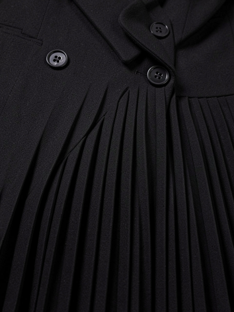 Close-up detail of pleated fabric and buttons on the blazer dress