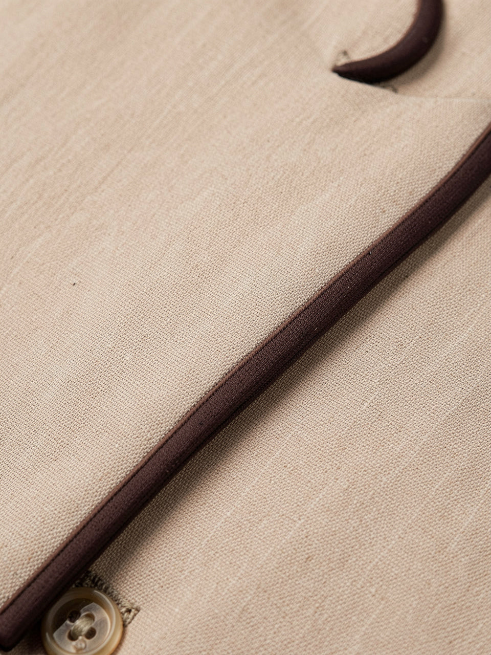 Close-up detail of contrast trim piping on beige blazer fabric