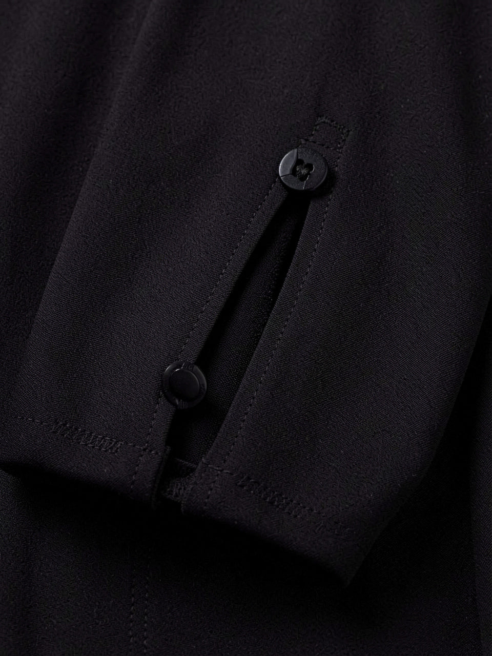 Close-up detail of decorative button and sleeve slit on midi dress