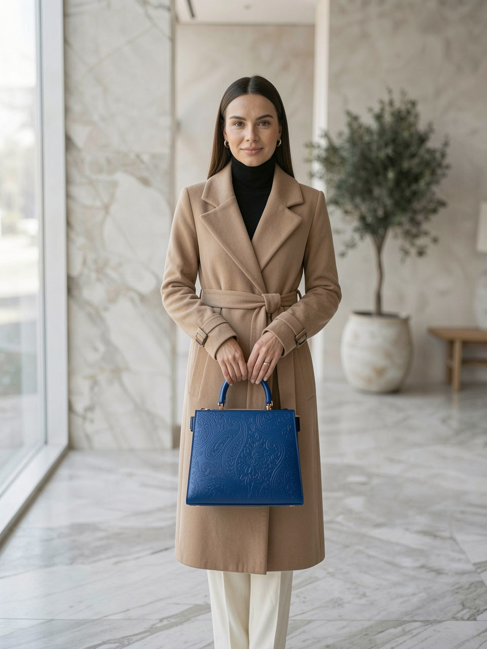 Top-Handle Handbag en azul, bolso estructurado con grabado floral paisley, modelo con abrigo beige en interior de mármol