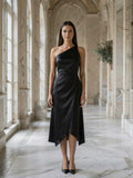 Black satin asymmetrical midi dress worn by model in marble old-money hallway