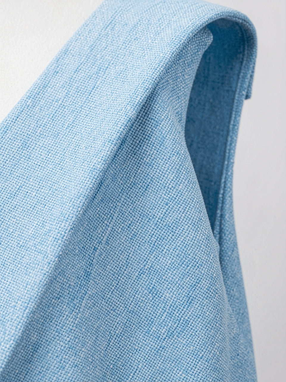 Close-up detail of light blue textured fabric and shoulder strap