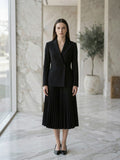 Model wearing black double-breasted pleated blazer dress in a marble old-money interior
